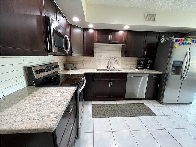 kitchen with sink, light tile patterned floors, appliances with stainless steel finishes, a textured ceiling, and decorative backsplash