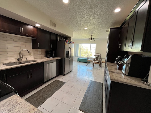 kitchen featuring light tile patterned flooring, sink, appliances with stainless steel finishes, ceiling fan, and backsplash