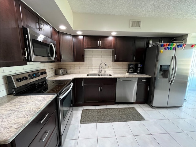 kitchen featuring sink, tasteful backsplash, dark brown cabinets, a textured ceiling, and stainless steel appliances