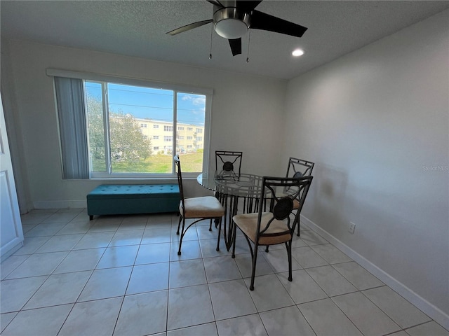 tiled dining space with ceiling fan and a textured ceiling