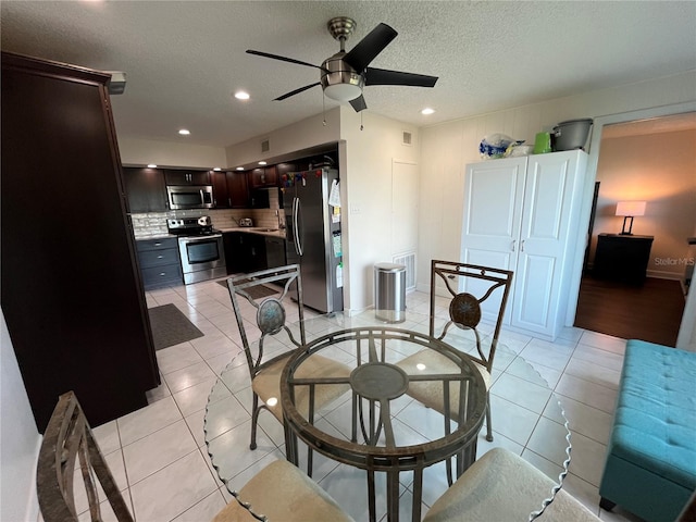 tiled dining room featuring ceiling fan, sink, and a textured ceiling