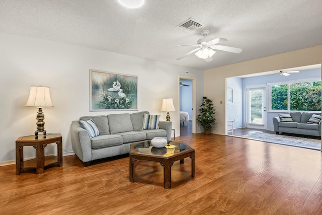 living room with hardwood / wood-style floors, a textured ceiling, and ceiling fan