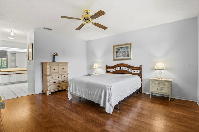 bedroom with connected bathroom, hardwood / wood-style flooring, a textured ceiling, and ceiling fan