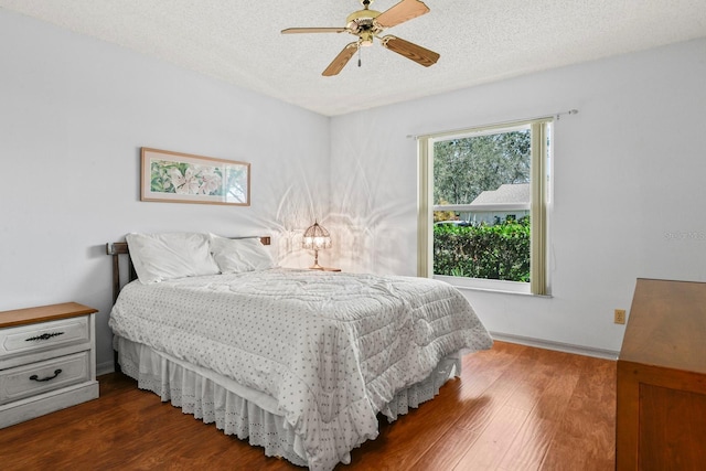 bedroom featuring ceiling fan, dark hardwood / wood-style floors, and a textured ceiling