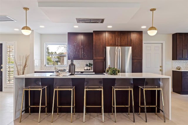 kitchen featuring pendant lighting, a breakfast bar, stainless steel refrigerator, and a kitchen island