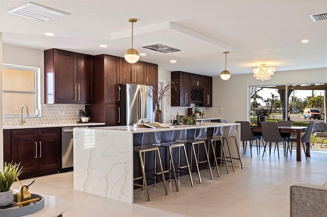 kitchen with sink, a kitchen breakfast bar, hanging light fixtures, a center island, and stainless steel appliances