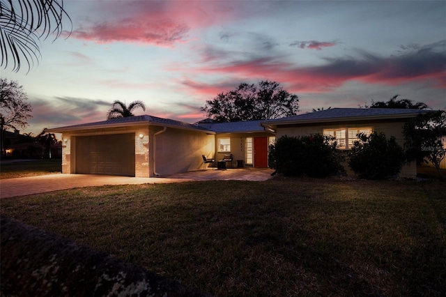 ranch-style home featuring a garage, a yard, and a patio area