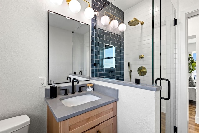 bathroom with vanity, hardwood / wood-style floors, a shower with shower door, and toilet