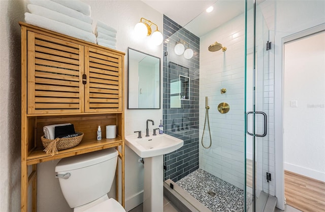 bathroom featuring a shower with door, hardwood / wood-style flooring, and toilet