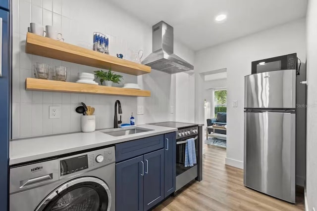 kitchen featuring appliances with stainless steel finishes, island range hood, washer / clothes dryer, blue cabinets, and sink