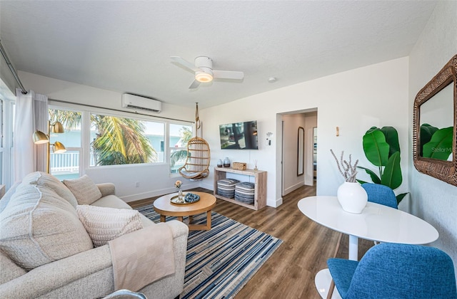 living room with ceiling fan, a textured ceiling, wood-type flooring, and a wall mounted AC