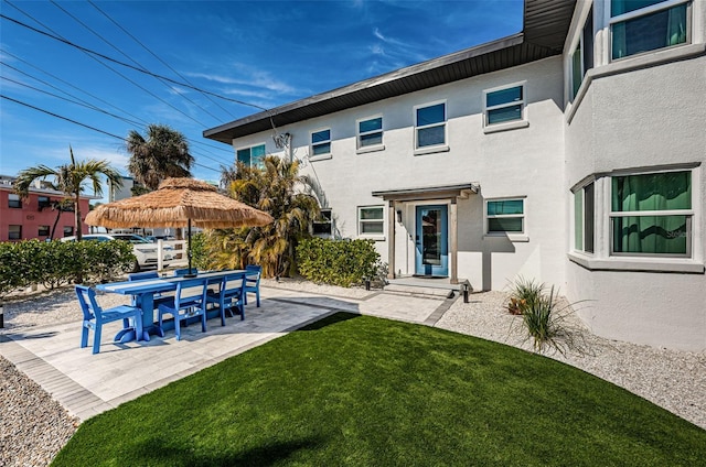 rear view of property with a patio and a lawn