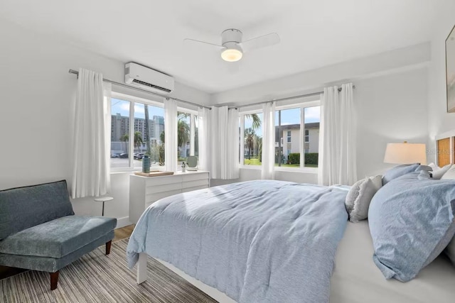 bedroom with wood-type flooring, a wall unit AC, and ceiling fan