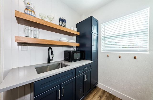 kitchen featuring tasteful backsplash, blue cabinets, dark hardwood / wood-style floors, and sink