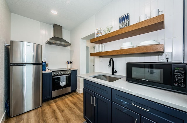 kitchen featuring sink, stainless steel appliances, light hardwood / wood-style floors, decorative backsplash, and wall chimney exhaust hood