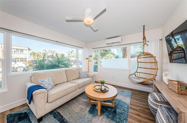 living room with wood-type flooring, an AC wall unit, ceiling fan, and a textured ceiling