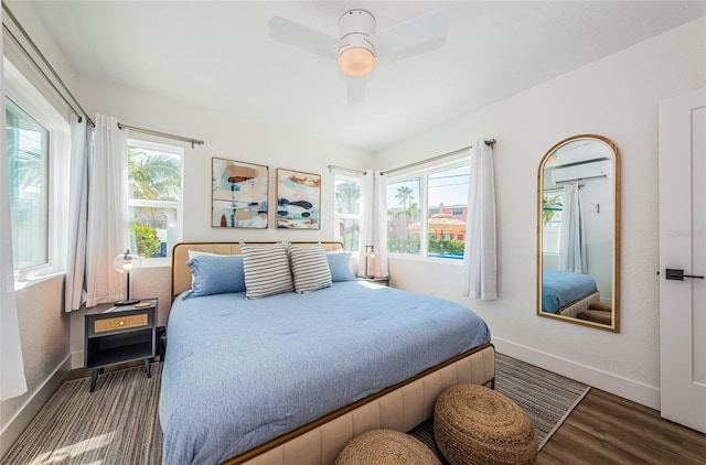 bedroom featuring multiple windows, a wall mounted air conditioner, dark wood-type flooring, and ceiling fan