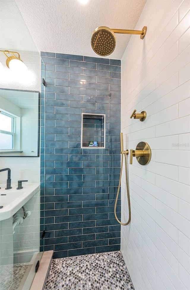 bathroom featuring a tile shower and a textured ceiling