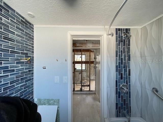 16333 Gulf Blvd Unit 105, Saint Petersburg, FL 33708 - bathroom with shower / tub combination, wood finished floors, a textured ceiling, and crown molding