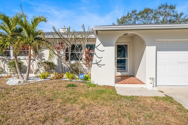 view of front of home featuring stucco siding, an attached garage, and a front yard