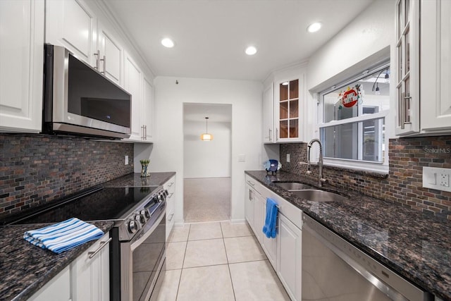 kitchen featuring dark stone countertops, stainless steel appliances, sink, and white cabinets