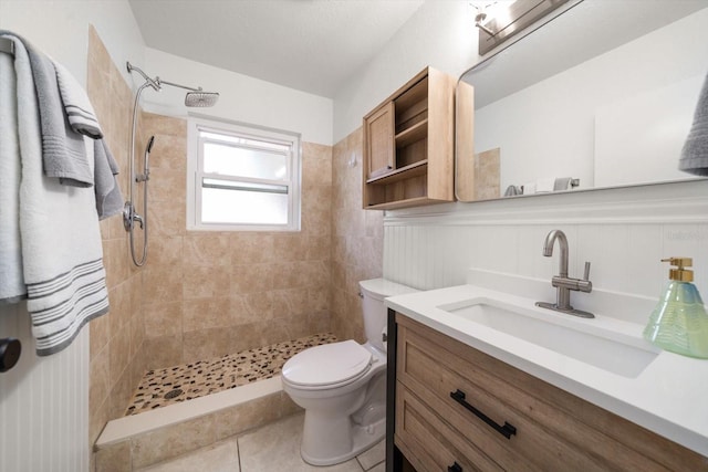 full bathroom featuring tile patterned flooring, toilet, vanity, and a tile shower