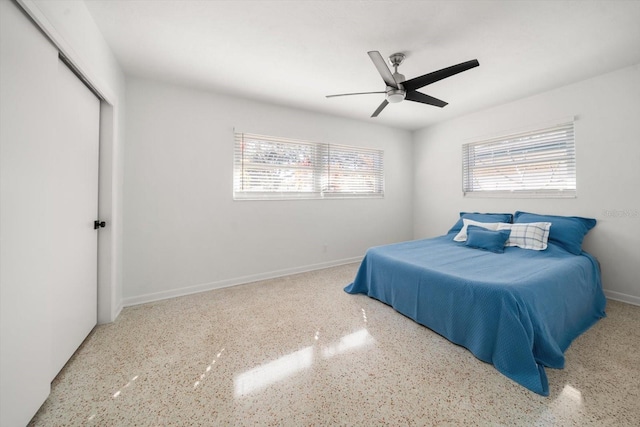 bedroom with a ceiling fan, baseboards, speckled floor, and a closet