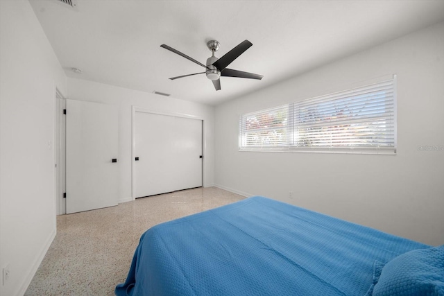 bedroom featuring baseboards, speckled floor, a closet, and ceiling fan