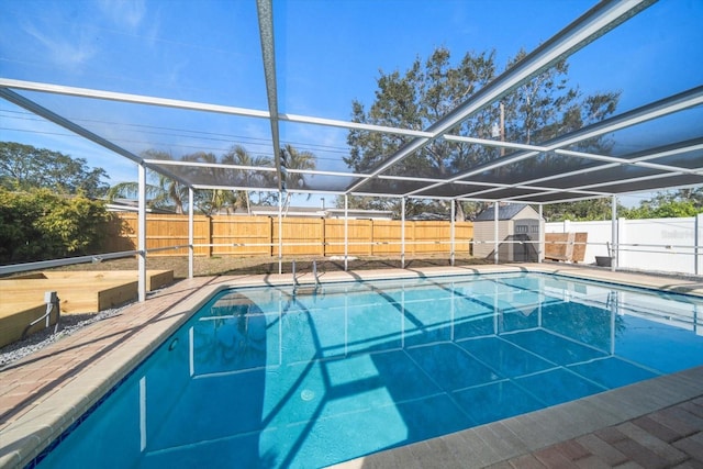 view of pool with a fenced backyard, a shed, glass enclosure, and an outdoor structure