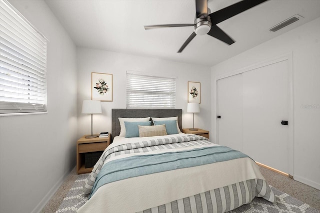 carpeted bedroom with a closet, visible vents, multiple windows, and a ceiling fan