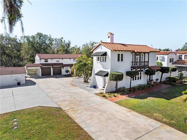 mediterranean / spanish house featuring a garage, a front yard, and a balcony