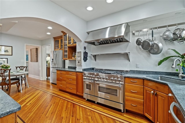 6010 17th Ave S, Gulfport, FL 33707 - kitchen with sink, appliances with stainless steel finishes, dark stone countertops, light hardwood / wood-style floors, and wall chimney exhaust hood