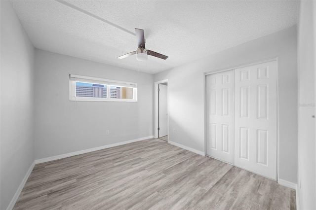 unfurnished bedroom with ceiling fan, a closet, light hardwood / wood-style flooring, and a textured ceiling