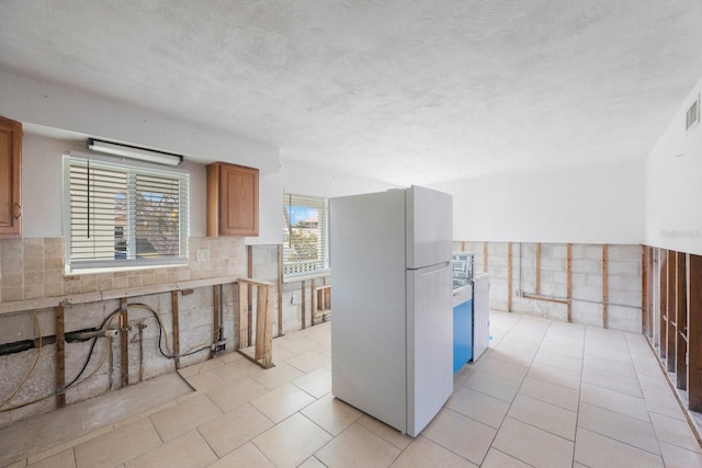 kitchen with tasteful backsplash, light tile patterned flooring, a textured ceiling, and white fridge