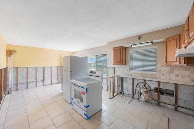 kitchen with tasteful backsplash, white fridge, range, and light tile patterned floors