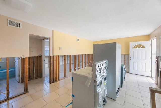 kitchen with washer / clothes dryer, light tile patterned floors, and stainless steel fridge