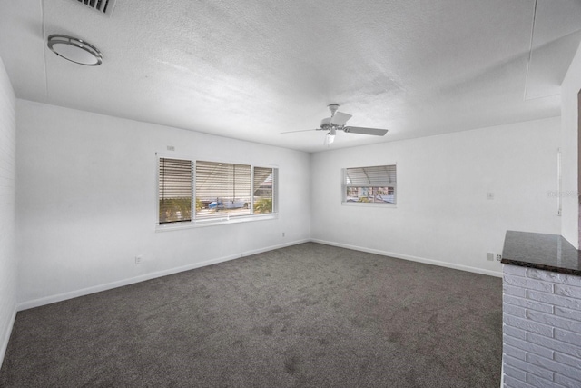 empty room with dark colored carpet, ceiling fan, and a textured ceiling