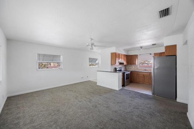 kitchen with appliances with stainless steel finishes, sink, ceiling fan, light carpet, and a textured ceiling