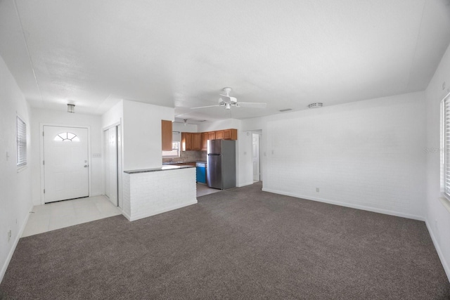 unfurnished living room with light carpet, ceiling fan, and brick wall