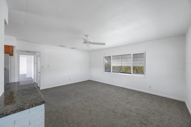 empty room featuring ceiling fan, a textured ceiling, and dark colored carpet