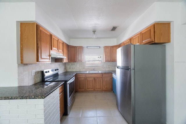 kitchen with tasteful backsplash, sink, dark stone countertops, light tile patterned floors, and stainless steel appliances