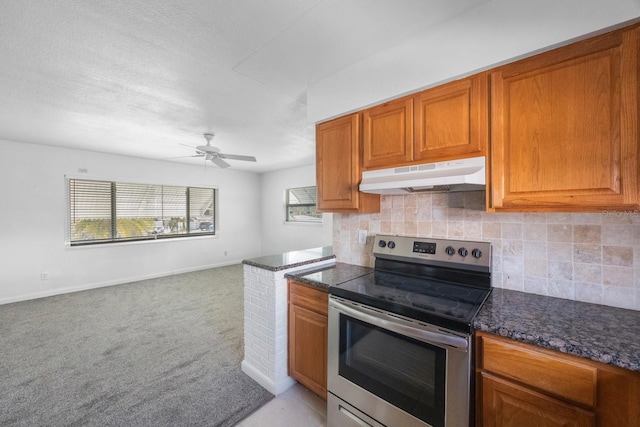 kitchen with dark stone countertops, light colored carpet, stainless steel range with electric cooktop, and decorative backsplash