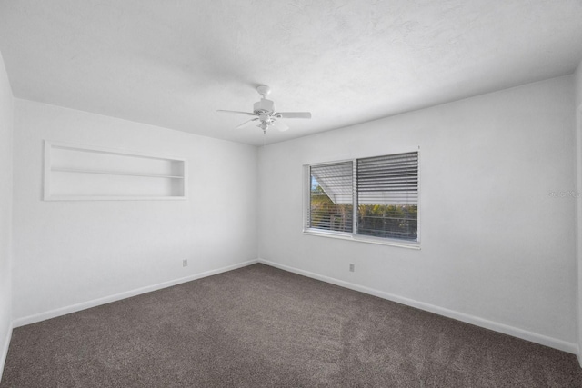 empty room featuring ceiling fan, a textured ceiling, dark carpet, and built in shelves