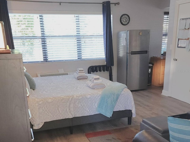 bedroom featuring hardwood / wood-style floors and stainless steel fridge