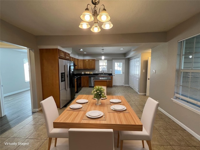 dining area with light tile patterned flooring, sink, and an inviting chandelier