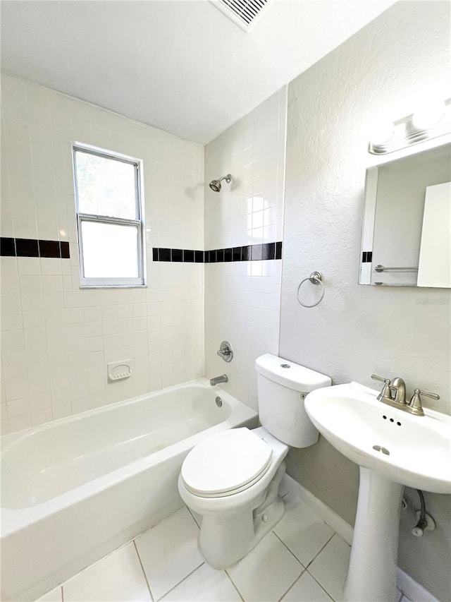 bathroom featuring tiled shower / bath, tile patterned floors, and toilet