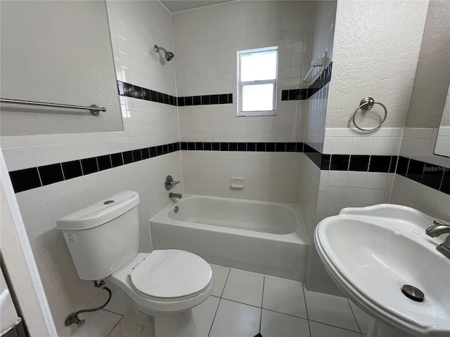 full bathroom with tile walls, sink, tiled shower / bath combo, and toilet