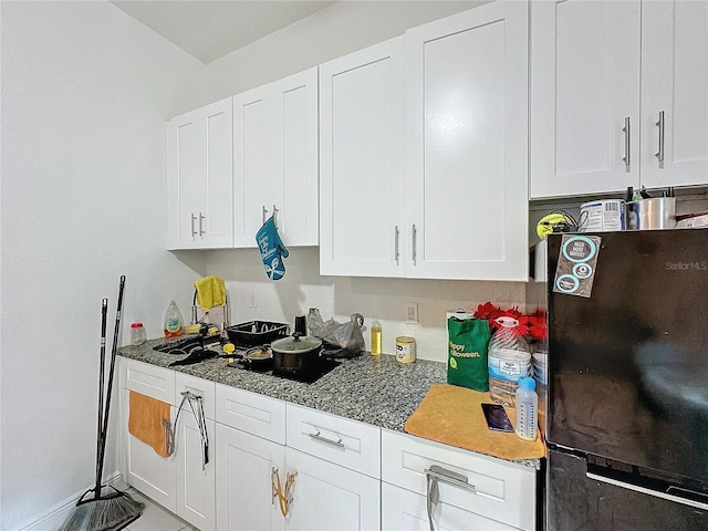3911 Auburndale Ave, Orlando, FL 32839 - kitchen featuring white cabinetry, black refrigerator, and stone countertops