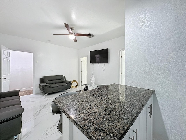 3911 Auburndale Ave, Orlando, FL 32839 - kitchen featuring white cabinetry, ceiling fan, a kitchen breakfast bar, and dark stone countertops