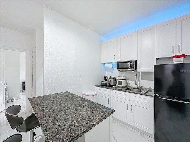 3911 Auburndale Ave, Orlando, FL 32839 - kitchen featuring black refrigerator, a breakfast bar, and white cabinets